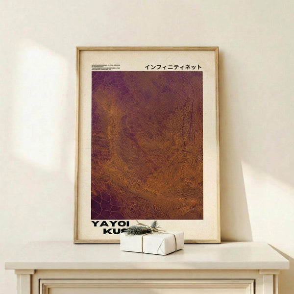 May include: Framed poster with Japanese text and textured purple-to-orange gradient pattern resembling organic cellular structures, displayed on light wood console table next to small wrapped gift with pine sprig, against cream wall in minimalist interior setting.