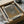 May include: Framed art print featuring abstract dotted pattern in muted gray and olive tones, displayed in black frame with white matting. Print shows organic flowing shapes created with small dots. Packaged in cardboard box with protective tissue paper, styled on white fabric surface with wooden dowels as props.