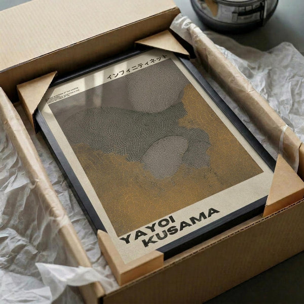 May include: Framed art print featuring abstract dotted pattern in muted gray and olive tones, displayed in black frame with white matting. Print shows organic flowing shapes created with small dots. Packaged in cardboard box with protective tissue paper, styled on white fabric surface with wooden dowels as props.