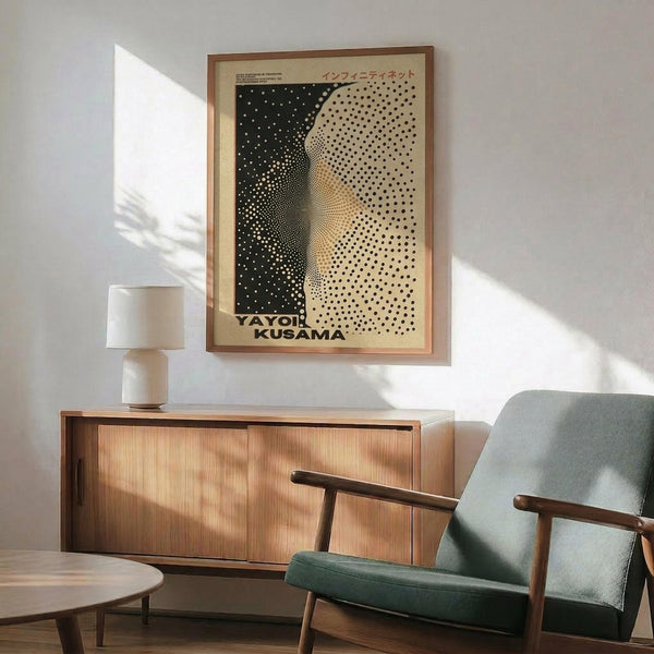 May include: Framed vintage-style poster with black and cream halftone dot pattern creating an abstract curved form, displayed above a wooden sideboard with white ceramic lamp. Mid-century modern living room setting features sage green upholstered armchair with wooden frame, round coffee table, and natural sunlight casting shadows on white wall.