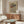 May include: Framed poster with flowing wavy lines in earth tones and colorful swirls, displayed above a mid-century modern walnut credenza in a bright living room with white curved chair, round glass coffee table, and minimalist decor