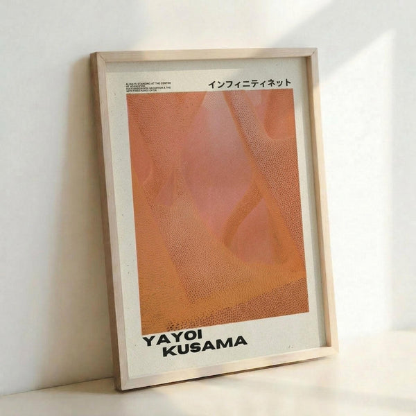 May include: Framed art print leaning against white wall featuring abstract orange and coral gradients with dotted halftone pattern. Japanese text at top, artist name at bottom in black letters. Natural wood frame with white matting, positioned on light surface with soft shadows.