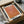 May include: Orange and coral gradient abstract art print with dotted texture pattern in black frame, displayed in cardboard shipping box with white tissue paper and wooden dowel packaging materials on neutral surface