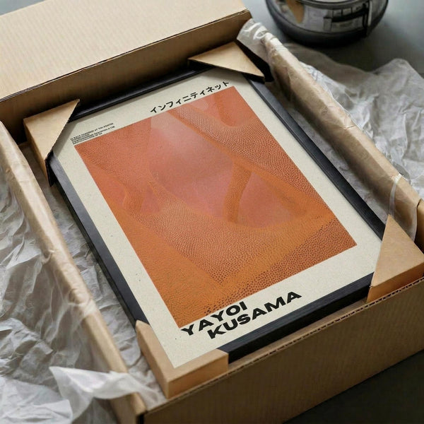 May include: Orange and coral gradient abstract art print with dotted texture pattern in black frame, displayed in cardboard shipping box with white tissue paper and wooden dowel packaging materials on neutral surface
