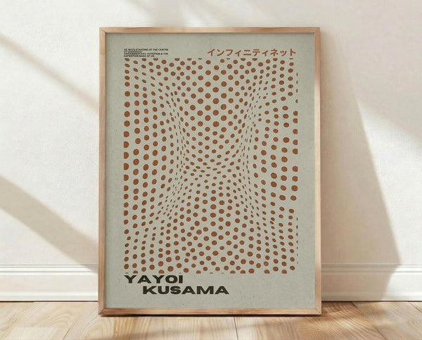 May include: Framed art print with optical illusion pattern of orange-brown dots on sage green background, creating tunnel-like depth effect. Features Japanese text and artist name in dark text. Natural wood frame leans against white wall on light wooden floor with soft natural lighting and shadows.
