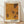 May include: Framed art print leaning against white wall on light wood floor. The poster features abstract orange and yellow dotted patterns with darker spotted areas creating organic, flowing shapes. Text reads "Tokyo 1998" and "YAYOI KUSAMA" in black letters. Natural wood frame with white matting. Soft natural lighting creates gentle shadows on the wall behind the artwork.