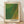 May include: Framed art print with green and yellow dotted pattern creating wavy, flowing abstract design. Features "Tokyo 1998" and "YAYOI KUSAMA" text at bottom with Japanese characters. Light wood frame with cream matting, leaning against white wall on light wooden floor with soft natural lighting casting shadows.