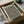 May include: Black and white abstract wavy line pattern artwork with small yellow dots, displayed in black frame inside cardboard shipping box with protective wrapping paper. Wooden frame pieces and tape roll visible nearby on white surface, showing unboxing scenario for wall art delivery.
