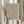 May include: Hands holding a framed poster with brown polka dots creating an optical illusion pattern on cream background. Japanese text appears at top. Person wears beige ruffled sleeves and holds dried wheat stems. Natural lighting creates soft shadows on neutral wall.