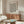 May include: Framed poster with black polka dot pattern on cream background displaying Japanese text, shown in modern living room with walnut sideboard, white sculptural chair, oval glass coffee table with colorful abstract art, and brass floor lamp against neutral walls.