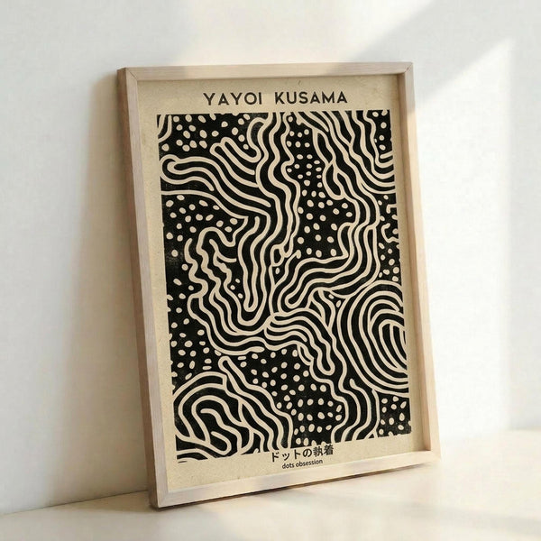 Framed black and white art print featuring flowing wavy lines and scattered polka dots in an abstract pattern reminiscent of Yayoi Kusama's style. The artwork is displayed in a light wooden frame against a white wall, with Japanese text at the bottom reading "dots obsession." The design shows organic curved forms interwoven with dotted areas creating a dynamic, hypnotic composition on cream-colored paper.
