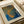 May include: Framed art print displayed on white surface with rolled paper tubes nearby. The artwork features abstract dotted patterns in blue, orange, and yellow tones creating flowing organic shapes. Japanese text appears vertically on the right side. The piece is matted in cream and shows pointillist-style technique with small circular dots forming larger curved forms against a blue background.