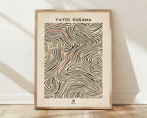 May include: Framed poster with abstract flowing black lines creating wave-like patterns on cream background, displayed against white wall on light wooden floor. Natural wood frame with warm brown tone. Soft shadows cast across scene. Text reads "YAYOI KUSAMA" at top and Japanese character with "waves" at bottom. Organic swirling lines form dynamic topographical design in minimalist earth tones.