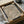 May include: Framed art print with flowing, swirling wave-like lines in black, brown, and cream tones, displayed in a cardboard shipping box with protective wrapping. The abstract topographical pattern creates organic, undulating forms across the surface. Wooden dowels and tissue paper are visible as packaging materials around the black-framed piece.