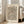May include: Framed art print featuring flowing organic wave patterns in black and terra cotta orange lines on cream background, displayed in light wood frame leaning against white wall next to beige upholstered sofa in bright, airy living room with large windows