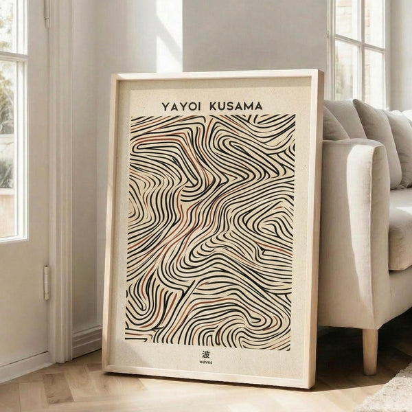 May include: Framed art print featuring flowing organic wave patterns in black and terra cotta orange lines on cream background, displayed in light wood frame leaning against white wall next to beige upholstered sofa in bright, airy living room with large windows