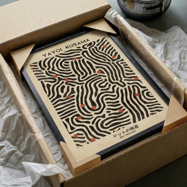 May include: Framed art print with abstract black curved lines and small red dots on cream background, displayed in black frame inside open cardboard shipping box with protective tissue paper and wooden dowels for packaging