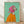 May include: Framed poster print leaning against white wall on wooden floor. Artwork shows Italian Greyhound dog wearing bright pink headscarf and orange sweater against mint green background. Painting has visible brushstrokes and portrait-style composition. Natural wood frame. Soft lighting creates gentle shadows on wall.