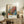 May include: Framed vintage-style Japanese art poster featuring colorful botanical illustration with orange, blue, and teal spherical flowers and foliage, displayed on rustic wooden console table alongside fern plant, ceramic vase, books, and beige upholstered chair in neutral-toned living room setting