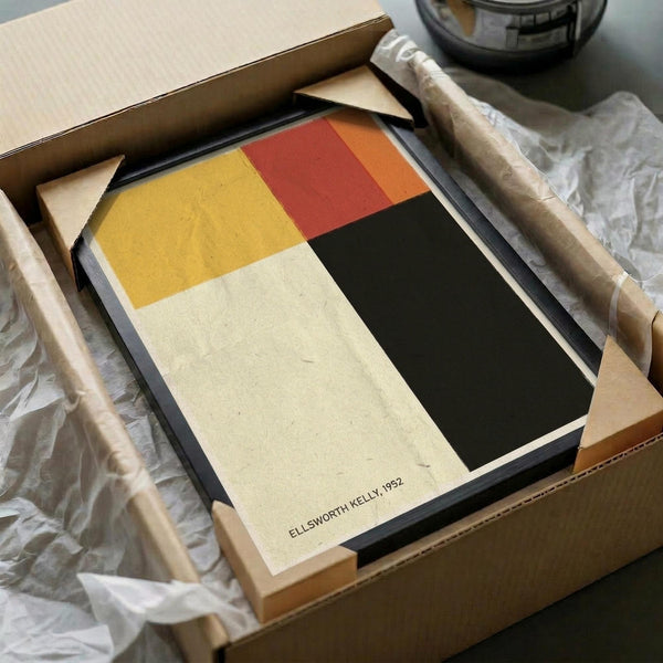 May include: Abstract geometric poster with four color blocks - yellow, red/orange, black, and cream sections - displayed in black frame inside cardboard shipping box with protective tissue paper and bubble wrap packaging materials visible around edges