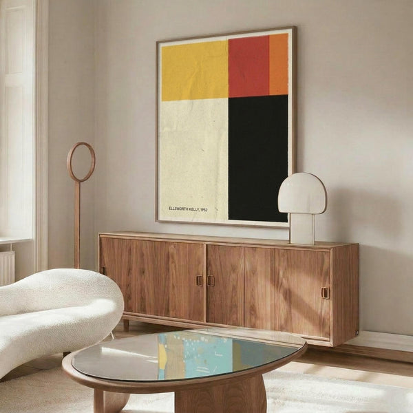 May include: Abstract geometric poster with yellow, red, orange, white, and black color blocks in thin frame, displayed above mid-century walnut credenza in modern living room with white sculptural chair, brass floor lamp, round glass coffee table, and neutral walls