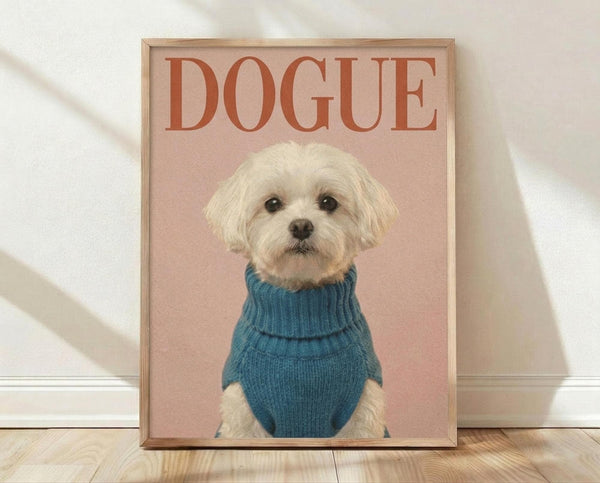 May include: Framed poster print leaning against white wall on wooden floor. Features small white fluffy dog wearing blue knit turtleneck sweater on dusty rose pink background. Bold orange text reads "DOGUE" above the dog. Light wooden frame with soft natural lighting casting diagonal shadows across the scene.