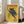 May include: Vintage-style poster with yellow background featuring black panther on tree branch, red "TOKYO" text at top and "JAPAN WEEK" at bottom, Japanese characters on left side, displayed in white frame leaning against white wall next to beige sofa in bright living room with hardwood floors and large windows.