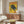 May include: Vintage-style yellow poster featuring a black panther with Japanese text, displayed above a mid-century modern wooden credenza in a contemporary living room. White sculptural chair and glass-top coffee table visible in foreground, with warm natural lighting creating reflections on the glossy surfaces.