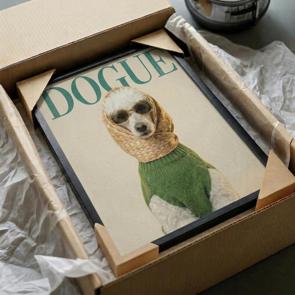 May include: Framed poster print in black frame being unpacked from cardboard shipping box with protective wrapping. Features white poodle wearing green knit sweater, sunglasses, and colorful plaid head scarf with "DOGUE" text in green letters above. Cream colored background with fashion magazine aesthetic. Surrounded by brown packing paper and tissue paper on neutral surface.