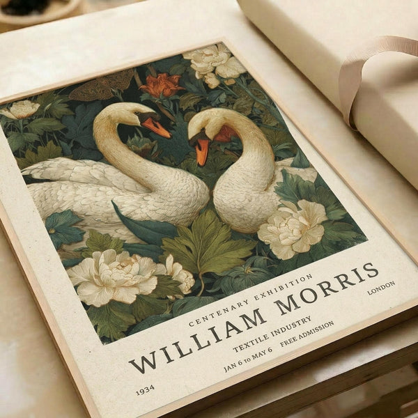 Vintage-style poster featuring two elegant white swans with orange beaks swimming among lush botanical elements including cream peonies, green water lilies, and detailed foliage on a dark teal background. The poster displays "William Morris" text and exhibition details including "1934", "Centenary Exhibition", "London", "Textile Industry", and "Jan 6 to May 6 Free Admission". The print appears on cream textured paper with a beige ribbon, photograph