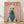 May include: Framed poster print leaning against white wall on light wood floor with soft natural lighting. Features a white poodle with curly groomed fur wearing a teal blue turtleneck sweater against a dusty pink background. Orange text reading "DOGUE" appears at top in magazine-style lettering. Thin natural wood frame surrounds the artwork.