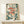 May include: Framed art print featuring three stylized red fish with spotted patterns and prominent black eyes, surrounded by teal botanical elements, coral-pink flowers, and scattered dots on cream background. Natural wood frame displayed on light wooden console table next to small white gift box with feather accent against white wall.