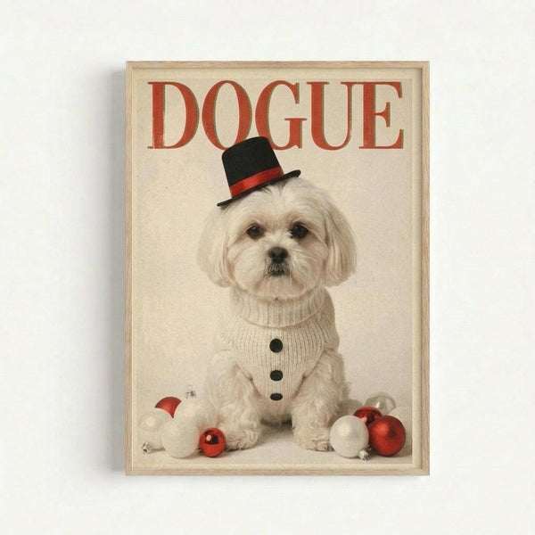 A framed poster featuring a white Maltese dog wearing a black top hat with red band and cream cable-knit sweater with black buttons. The dog sits against a light background with red and white Christmas ornaments scattered around its paws. "DOGUE" appears in large red letters at the top, styled like a fashion magazine cover. The artwork is displayed in a light wood frame against a white wall.
