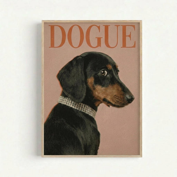A framed poster featuring a black and tan dachshund in profile wearing a sparkly rhinestone collar against a dusty pink background. The word "DOGUE" appears in large orange serif letters at the top, mimicking the style of a high-end fashion magazine cover. The dog has a sleek coat with tan markings on the face and chest, and gazes elegantly to the right. The poster is displayed in a thin light wood frame against a white wall.