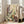 May include: Large framed botanical artwork leaning against white wall next to beige sofa in bright living room. The poster features stylized wildflowers and plants in dotted patterns with white daisies, purple lavender spikes, yellow blooms, and rust-colored foliage against cream background. Natural wood frame, hardwood floors visible.