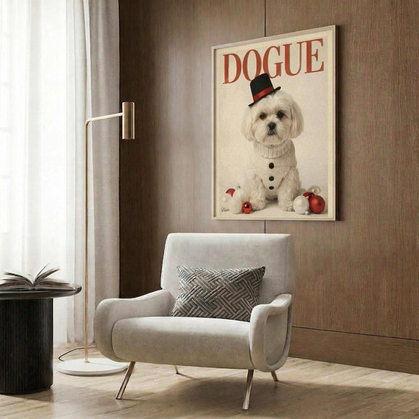 May include: Framed poster print hanging on wood-paneled wall above modern beige armchair with geometric pillow. Print shows white Maltese dog wearing black top hat with red band and cream cable-knit sweater, sitting with red and white Christmas ornaments. Red "DOGUE" text at top. Gold floor lamp and side table with open book visible in contemporary living room setting.