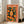 May include: Framed poster leaning against white wall next to beige sofa in bright living room. Orange-themed artwork features woman with closed eyes and long dark hair surrounded by citrus slices and green leaves. Vintage travel poster style with "TOKYO - JAPAN" text and Japanese characters. White frame, natural lighting from windows.