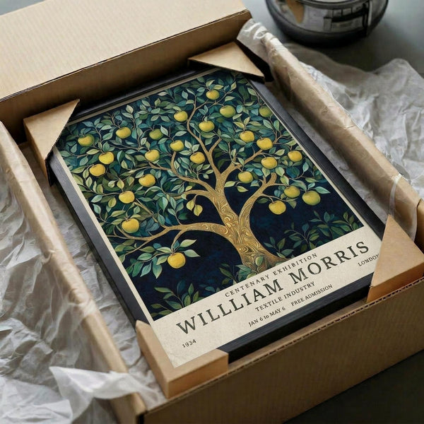 May include: Vintage-style botanical poster featuring an ornate fruit tree with golden apples and green foliage against a dark blue background, displayed in a black frame inside an open cardboard shipping box with protective packaging materials on a white surface.