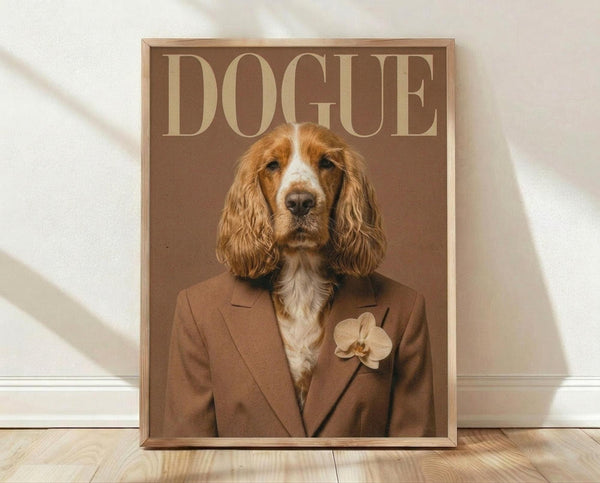 May include: Framed poster print leaning against white wall on wooden floor. Brown-toned fashion magazine cover featuring a spaniel dog wearing a tan blazer with orchid boutonniere. The dog has wavy reddish-brown and white fur with long ears. Large "DOGUE" text at top in cream letters on rich brown background. Warm, sophisticated styling with monochromatic color palette.
