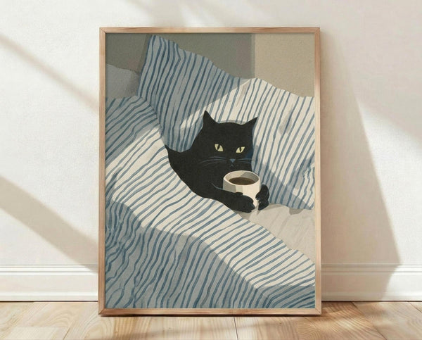 May include: Framed poster print leaning against white wall on light wood floor. Artwork shows black cat with bright yellow eyes lying on blue and white striped bedding or fabric, holding white coffee mug. Illustration uses soft, muted color palette with organic flowing lines. Natural wood frame surrounds the print. Gentle shadows cast across white textured wall background.