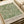 May include: Vintage-style botanical poster with intricate green leaf pattern on cream background, displayed on neutral wrapping paper with beige ribbon. The design features flowing willow-like branches and foliage in an Arts and Crafts style. Text at bottom reads "William Morris Centenary Exhibition" with exhibition details. Soft, muted tones create an elegant, timeless aesthetic.