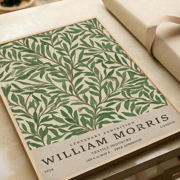 May include: Vintage-style botanical poster with intricate green leaf pattern on cream background, displayed on neutral wrapping paper with beige ribbon. The design features flowing willow-like branches and foliage in an Arts and Crafts style. Text at bottom reads "William Morris Centenary Exhibition" with exhibition details. Soft, muted tones create an elegant, timeless aesthetic.
