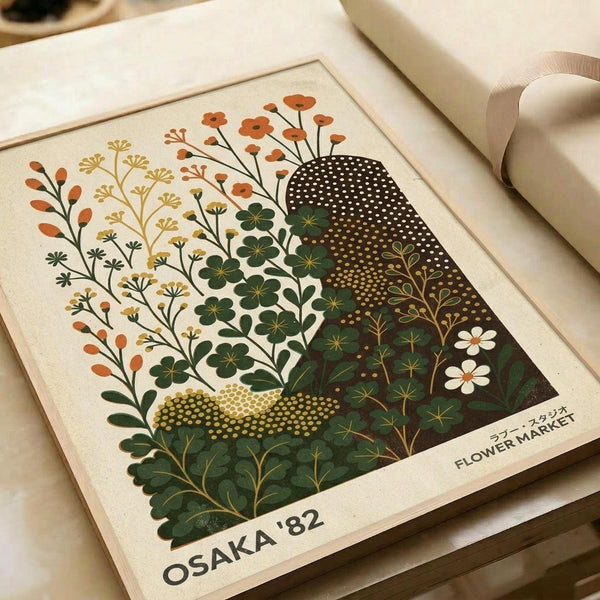May include: Vintage-style botanical poster print in cream mat frame showing stylized wildflowers and foliage in orange, yellow, and green tones with geometric dotted patterns, displayed on white bedding next to cream ribbon, featuring "OSAKA '82 FLOWER MARKET" text at bottom in retro Japanese design aesthetic