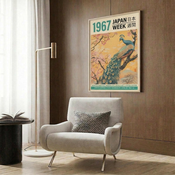 May include: A vintage-style poster featuring a blue and teal peacock perched on flowering cherry blossom branches against a warm yellow-orange background, displayed in a light wood frame on a textured brown wood panel wall. The scene shows a modern beige upholstered chair with geometric patterned pillow, brass floor lamp, and dark round side table with an open book, creating a contemporary living room setting.