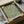 May include: Framed botanical art print featuring flowing green foliage pattern on cream background, displayed in black frame inside cardboard shipping box with protective tissue paper and wooden dowels for packaging.