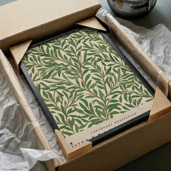 May include: Framed botanical art print featuring flowing green foliage pattern on cream background, displayed in black frame inside cardboard shipping box with protective tissue paper and wooden dowels for packaging.