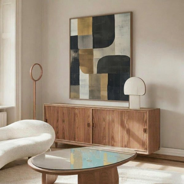 May include: Abstract geometric artwork in frame with muted palette of sage green, mustard yellow, cream, and charcoal blocks and curved shapes, displayed above walnut credenza in modern living room with white textured chair, glass coffee table, and minimalist floor lamp