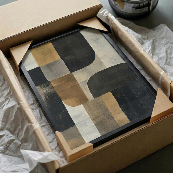 May include: Abstract geometric poster with earth-toned shapes in charcoal, beige, brown and cream displayed in black frame inside cardboard shipping box with protective tissue paper and wooden dowel rod visible alongside