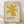 May include: Framed art print featuring a golden yellow abstract star or flower-like shape with eight pointed rays on cream textured background. Text below reads "ELLSWORTH KELLY" and "Aloes, 1958" in dark letters. Natural wood frame sits on light wooden floor against white wall with soft shadows from natural lighting.