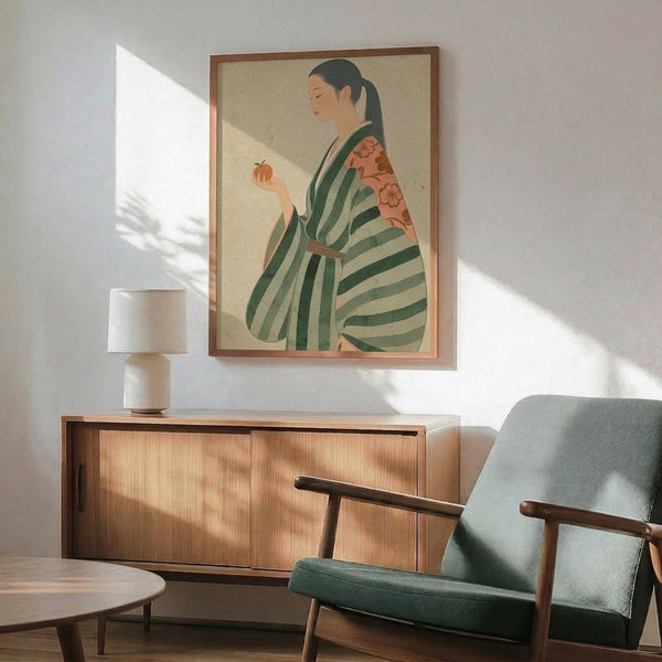 May include: Framed poster showing Japanese woman in green striped kimono with coral floral sleeves, holding persimmon fruit, displayed above wood sideboard with white ceramic table lamp in modern living room setting with sage green upholstered chair and natural lighting casting shadows on white wall